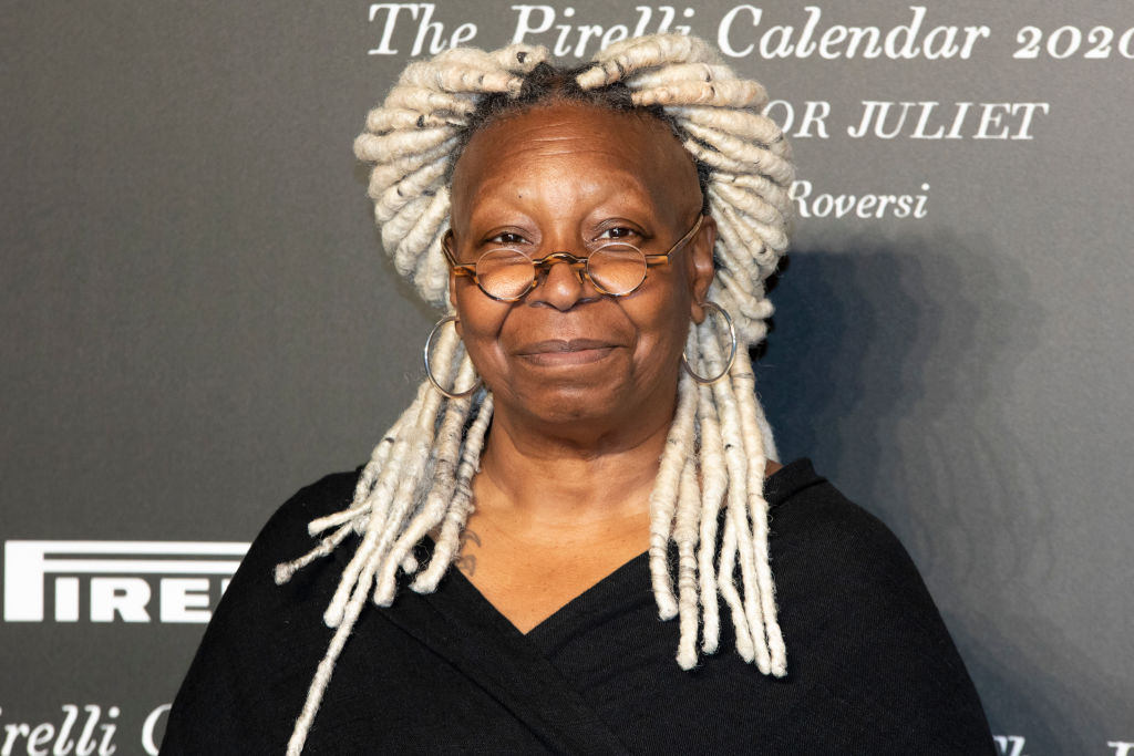 Whoopi Goldberg with blond dreadlocks wearing a black dress