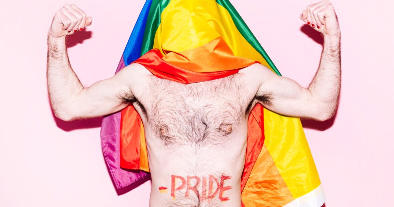 A gay otter flexing his arms with a Pride flag draped over his head