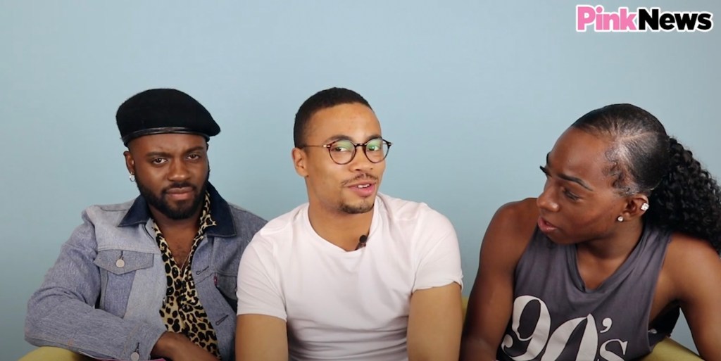 This is an image of three Black men sitting on a couch. The man on the far left is wearing a beret and has a beard. The man in the middle is wearing a white tshirt and has round glasses. The man on the righ has long hair and is wearing a black tank top