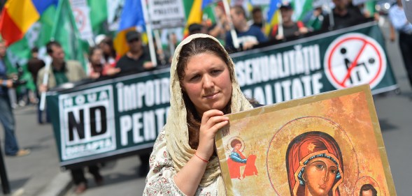 A Romanian woman holds an Orthodox icon as she marches with Romanian flag during a protest against incoming Gay Pride in Bucharest on June 8, 2013.