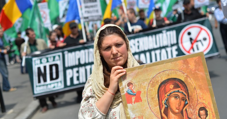 A Romanian woman holds an Orthodox icon as she marches with Romanian flag during a protest against incoming Gay Pride in Bucharest on June 8, 2013.