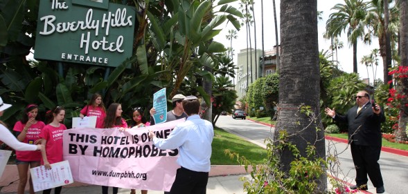 A security guard confronts demonstrators protesting the introduction of laws targeting women and LGBT people in Brunei, outside the Sultan-owned Beverley Hills Hotel