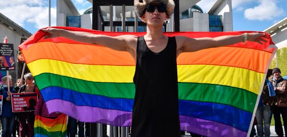 An activist displays a rainbow flag in front of the Chancellery in Berlin on April 30, 2017, during a demonstration calling on Russian President to put an end to the Chechnya anti-gay purge.