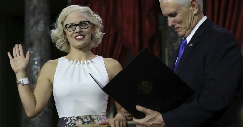 US Senator from Arizona Kirsten Sinema holds a law book as she is sworn in by Vice President Mike Pence on January 3, 2019.