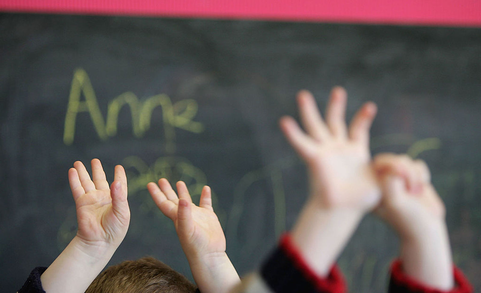 Children in school raise their hands as they learn about LGBT relationships.