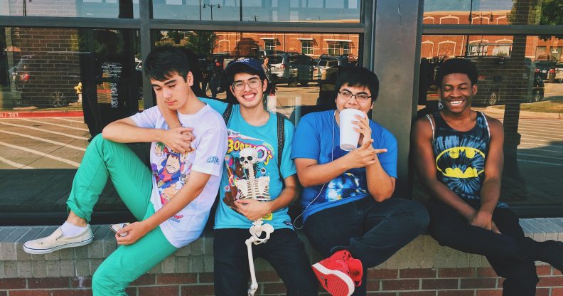 Four teenage boys sitting on a wall