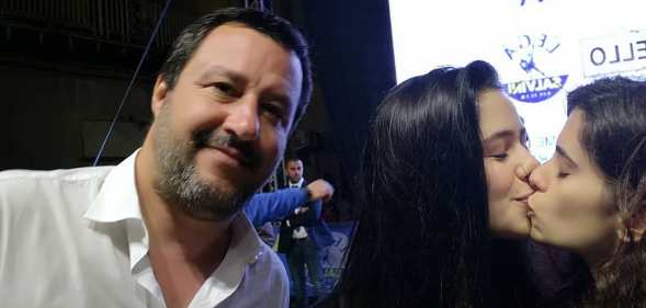 Matteo Salvini next to two women kissing.