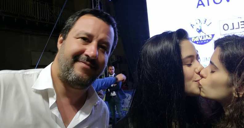 Matteo Salvini next to two women kissing.