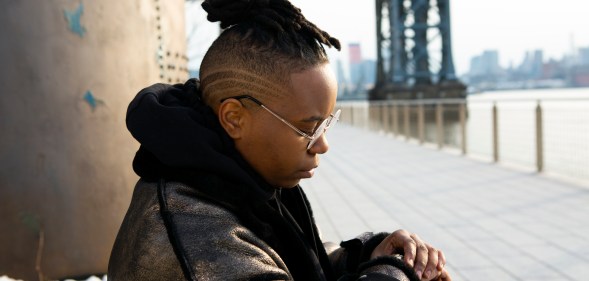 A transmasculine person checking his watch in a park