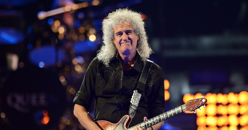 Brian May holds his guitar while on stage