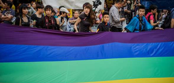 Participants carry a large flag as they take part in a Gay Pride procession in Hong Kong on November 10, 2012. As anti-discrimination laws continues to expand globally, the participant marched to promote equal rights for lesbian, gay, bisexual and transgender (LGBT). AFP PHOTO / Philippe Lopez (Photo credit should read PHILIPPE LOPEZ/AFP/Getty Images)