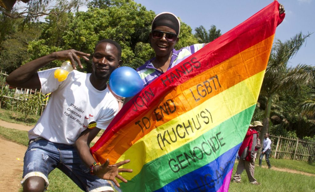 Ugandan men hold a rainbow flag reading "Join hands to end LGBTI (Lesbian Gay Bi Trans Intersex - called Kuchu in Uganda) genocide" as they celebrate on August 9, 2014 during the annual gay pride in Entebbe, Uganda. Uganda's attorney general has filed an appeal against the constitutional court's decision to overturn tough new anti-gay laws, his deputy said on August 9. Branded draconian and "abominable" by rights groups but popular domestically, the six-month old law which ruled that homosexuals would be jailed for life was scrapped on a technicality by the constitutional court on August 1. AFP PHOTO/ ISAAC KASAMANI (Photo credit should read ISAAC KASAMANI/AFP/Getty Images)