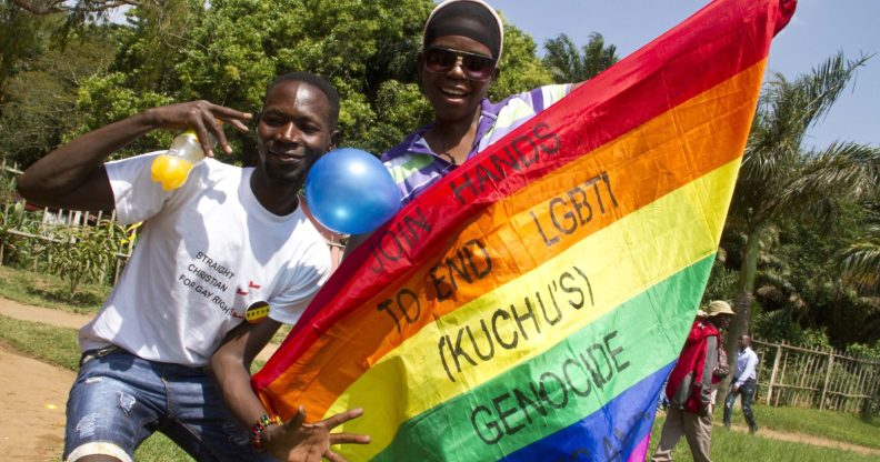 Uganda men hold a rainbow flag reading "Join hands to end LGBTI (Lesbian Gay Bi Trans Intersex - called Kuchu in Uganda) genocide" as they celebrate on August 9, 2014 during the annual gay pride in Entebbe, Uganda. Uganda's attorney general has filed an appeal against the constitutional court's decision to overturn tough new anti-gay laws, his deputy said on August 9. Branded draconian and "abominable" by rights groups but popular domestically, the six-month old law which ruled that homosexuals would be jailed for life was scrapped on a technicality by the constitutional court on August 1. AFP PHOTO/ ISAAC KASAMANI (Photo credit should read ISAAC KASAMANI/AFP/Getty Images)