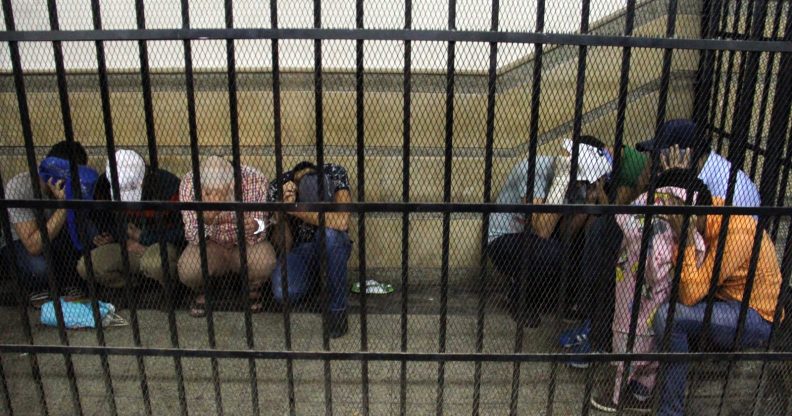 Eight Egyptian men on trial for doing a video prosecutors claimed was of a gay wedding hide their identities as they sit in the defendent's cage during their trial in Cairo on November 1, 2014. The video, filmed aboard a Nile riverboat, shows what prosecutors said was a gay wedding ceremony, with two men in the centre kissing, exchanging rings and cutting a cake with their picture on it. The Egyptian court jailed the eight men for three years. AFP PHOTO / STR (Photo credit should read -/AFP/Getty Images)