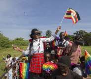 People waving Ugandan and rainbow flags take part in the Gay Pride parade in Entebbe on August 8, 2015. Ugandan activists gathered for a gay pride rally, celebrating one year since the overturning of a strict anti-homosexuality law but fearing more tough legislation may be on its way. Homosexuality remains illegal in Uganda, punishable by a jail sentence. AFP PHOTO/ ISAAC KASAMANI (Photo credit should read ISAAC KASAMANI/AFP/Getty Images)