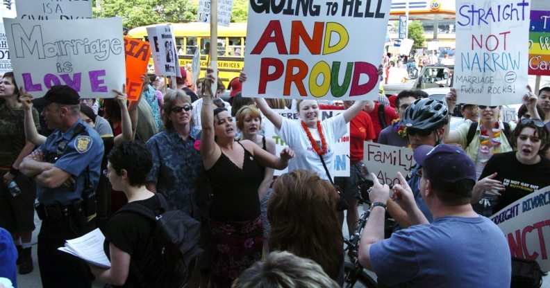 SEATTLE - MAY 1: Protestors hold signs and greet participants to a rally to affirm traditional marriage between a man and a woman on May 1, 2004 at Safeco Field in Seattle. The special speaker was James Dobson, founder of the evangelical Christian group called "Focus on the Family". The event was organized by local Christian groups and drew approximately 20,000 people as well as about 3,000 protestors, according to police. (Photo by Ron Wurzer/Getty Images)