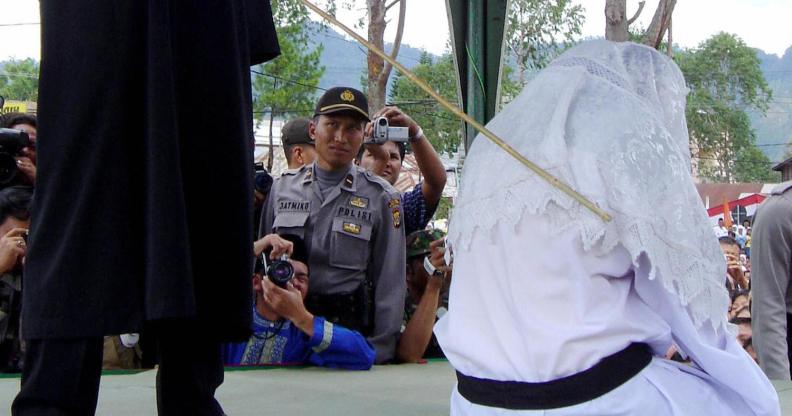 TAKENGON, INDONESIA: An Acehnese executor flogs a convicted woman in Takengon, in Indonesian central Aceh province, 19 August 2005 after an Islamic sharia court ordered four women to be flogged for petty gambling offences. The public lashing was the second since the Indonesian government allowed the western province to implement religious law as part of broader autonomy granted in 2001 to curb a separatist Islamist insurgency. AFP PHOTO (Photo credit should read STR/AFP/Getty Images)