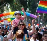 A woman carrying a child on her shoulder waves a rainbow flag during the opening event of the annual Gay Pride parade in the Israeli city of Tel Aviv, on June 3, 2016. (JACK GUEZ/AFP/Getty)