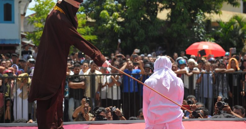 A religious officer canes an Acehnese youth onstage as punishment for dating outside of marriage, which is against sharia law, outside a mosque in Banda Aceh on August 1, 2016. The strictly Muslim province, Aceh has become increasingly conservative in recent years and is the only one in Indonesia implementing Sharia law. / AFP / CHAIDEER MAHYUDDIN (Photo credit should read CHAIDEER MAHYUDDIN/AFP/Getty Images)