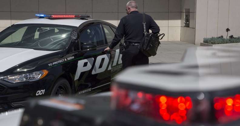 An LAPD officer, thepolice force currently investigating the second death of a black man at the home of gay Democrat donor Ed Buck, looks at a car.