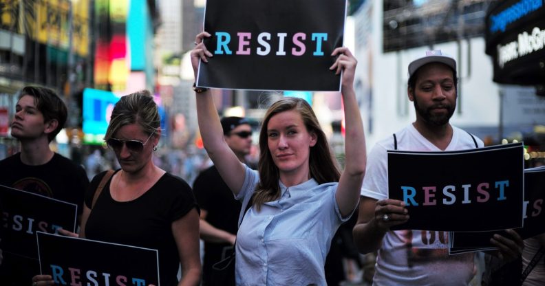 Protesters display placards against US President Donald Trump during a demonstration in front of the US Army career center in Times Square, New York, on July 26, 2017. Trump announced on July 26 that transgender people may not serve "in any capacity" in the US military, citing the "tremendous medical costs and disruption" their presence would cause. / AFP PHOTO / Jewel SAMAD (Photo credit should read JEWEL SAMAD/AFP/Getty Images)