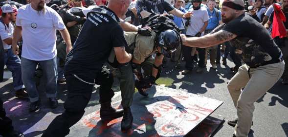 CHARLOTTESVILLE, VA - AUGUST 12: White nationalists, neo-Nazis, the KKK and members of the "alt-right" attack each other as a counter protester (R) intervenes during the melee outside Emancipation Park during the Unite the Right rally August 12, 2017 in Charlottesville, Virginia. After clashes with anti-fascist protesters and police the rally was declared an unlawful gathering and people were forced out of Lee Park, where a statue of Confederate General Robert E. Lee is slated to be removed. (Photo by Chip Somodevilla/Getty Images)