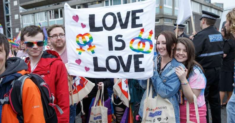 People hold up a sign during Glasgow Pride.