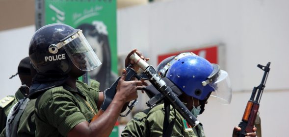 Zambian riot policeman gets ready to fire a tear gas canister to disperser Zambian traders and vendors during a march to protest over a ban on street commerce aimed at curbing a deadly cholera outbreak, in Lusaka, on January 15, 2018. Police in Zambia's capital Lusaka fired tear gas at angry traders marching to the president's office. The 500-strong crowd was trying to deliver a petition to President Edgar Lungu who has become the public face of the campaign against the outbreak that has claimed at least 70 lives since September. Authorities have banned several street markets in Lusaka in an effort to reduce the volume of food and drink sold in unsanitary open-air locations, which are particularly vulnerable to the spread of cholera. / AFP PHOTO / DAWOOD SALIM (Photo credit should read DAWOOD SALIM/AFP/Getty Images)