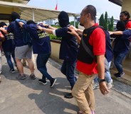 Indonesian police guard men arrested in a recent raid during a press conference at a police station in Jakarta on May 22, 2017. Indonesian police have detained 141 men who were allegedly holding a gay party at a sauna, an official said on May 22, the latest sign of a backlash against homosexuals in the Muslim-majority country. / AFP PHOTO / FERNANDO (Photo credit should read FERNANDO/AFP/Getty Images)