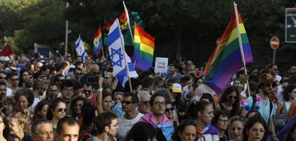 Participants wave Israeli and LGBT pride rainbow flags during Jerusalem's annual Gay Pride parade on August 2, 2018.