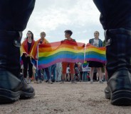 People wave rainbow flags during a pride rally in Saint Petersburg, on Agust 12, 2017 as police look on.