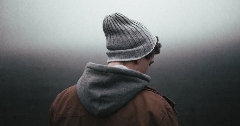 A man wearing a beanie hat and hoody looking away from the camera