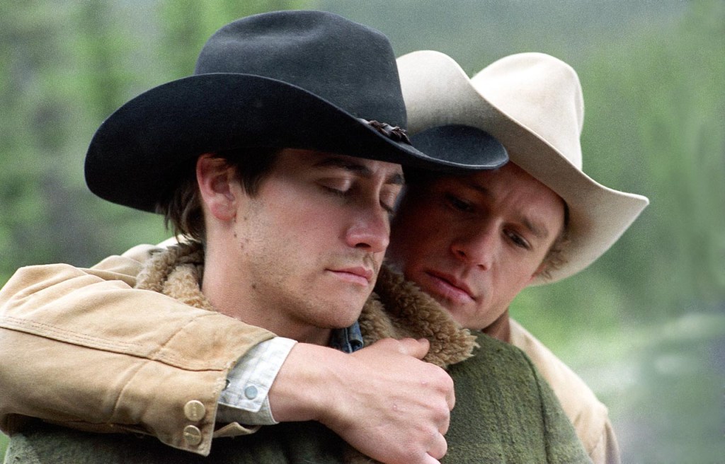 A still from the 2005 film Brokeback Mountain showing actors Jake Gyllenhaal and Heath Ledger dressed in their cowboy outfits with Ledger standing close to Gyllenhaal with his arm around him