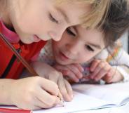 Two children draw a picture together, similar to the images Russian Police seized from a school.