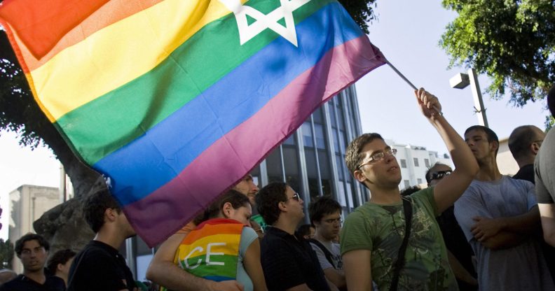 An Israeli man waves a Pride rainbow flag bearing the Star of David