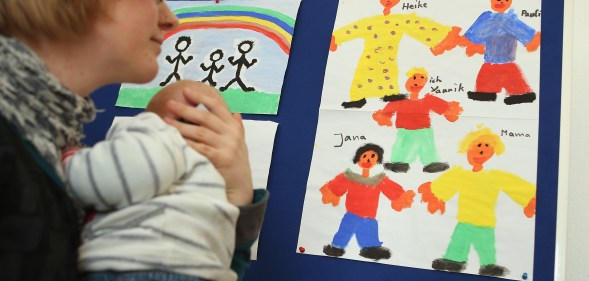 A woman holding a baby looking at drawings. She is at Germany's first gay parent counselling centre.