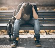 Boy holds his head in his hands as he sits on a bench