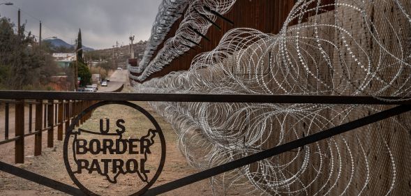 A metal fence marked with the US Border Patrol sign prevents people to get close to the barbed wire covering the US/Mexico border fence