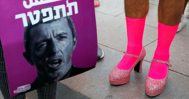 Members of the LGBT community hold a banner reading in Hebrew 'A homophobic Racist Has to Quit' during a rally against Israel's Education Minister Rafi Peretz following his remarks on gay conversion therapy, in the Israeli coastal city of Tel Aviv on July 14, 2019.