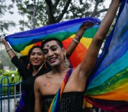 Two smiling people hold a rainbow flag