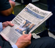 A man reads The Times newspaper as he rides the tube in London