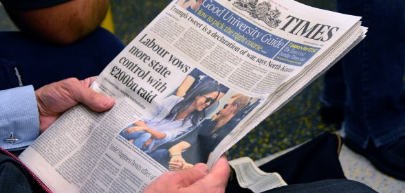 A man reads The Times newspaper as he rides the tube in London