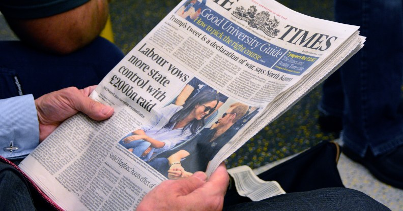 A man reads The Times newspaper as he rides the tube in London