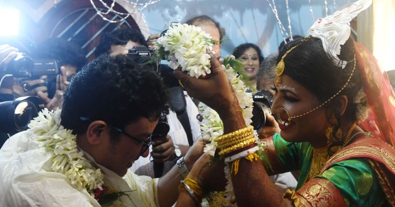 A bride places a garland over her groom's head