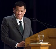 Rodrigo Duterte speaking at a lectern, wearing a black suit and tie