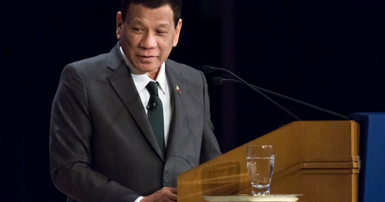 Rodrigo Duterte speaking at a lectern, wearing a black suit and tie