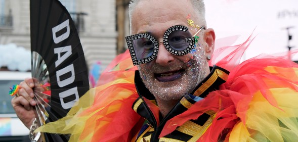 Pride participant seen with rainbow feathers and a "Daddy" fan