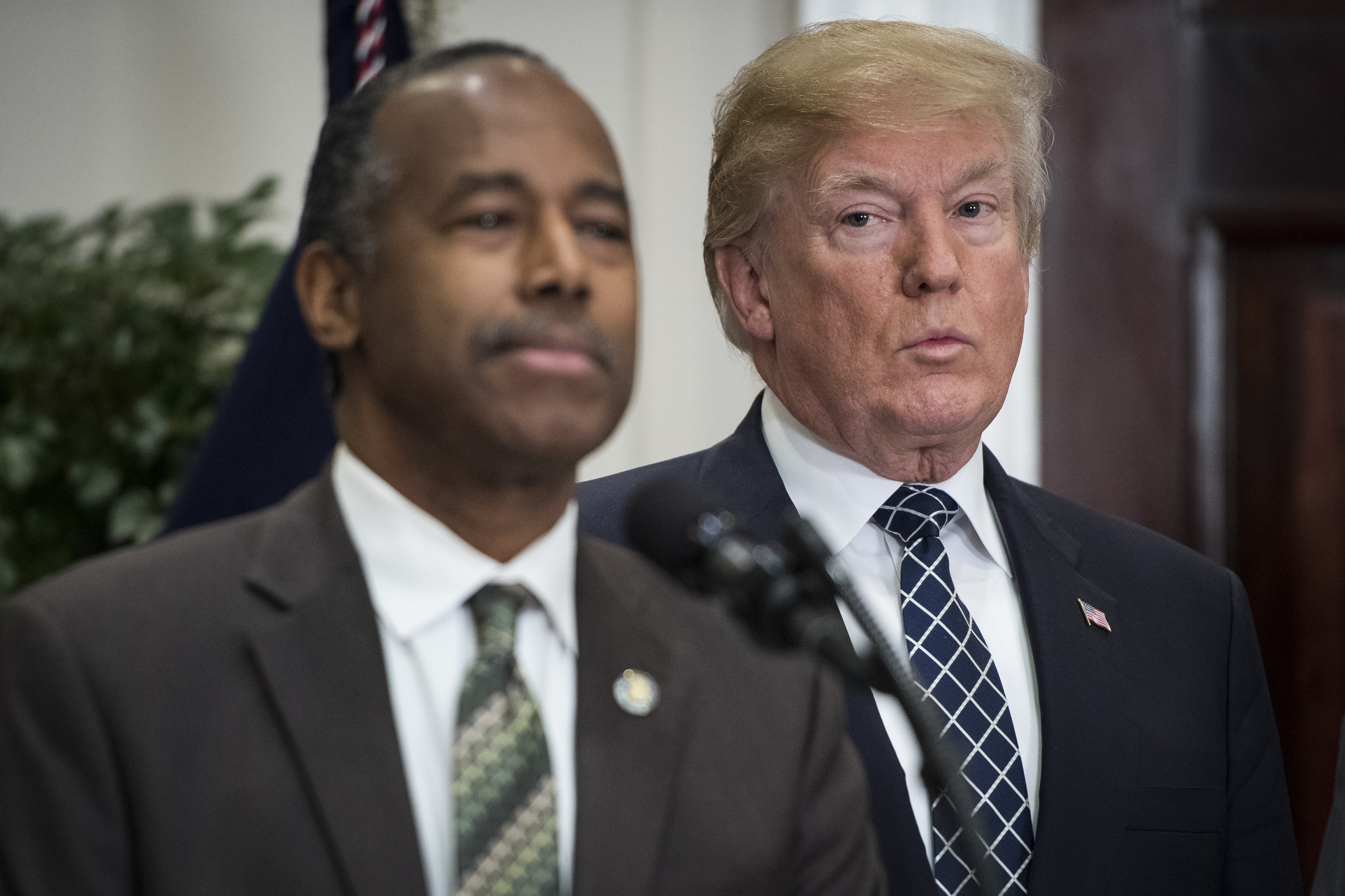 President Donald Trump listens as Secretary of Housing and Urban Development Ben Carson speaks