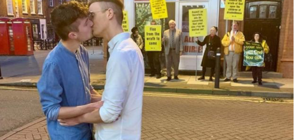 A gay couple showed their defiance against a group of religious protesters in the best way possible. (Joe Fergus and Robert Brookes)