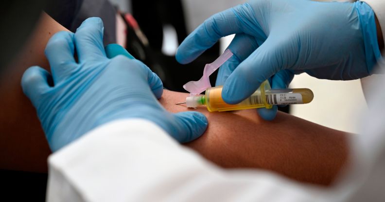 A technician extracts blood from a patient for an HIV test.